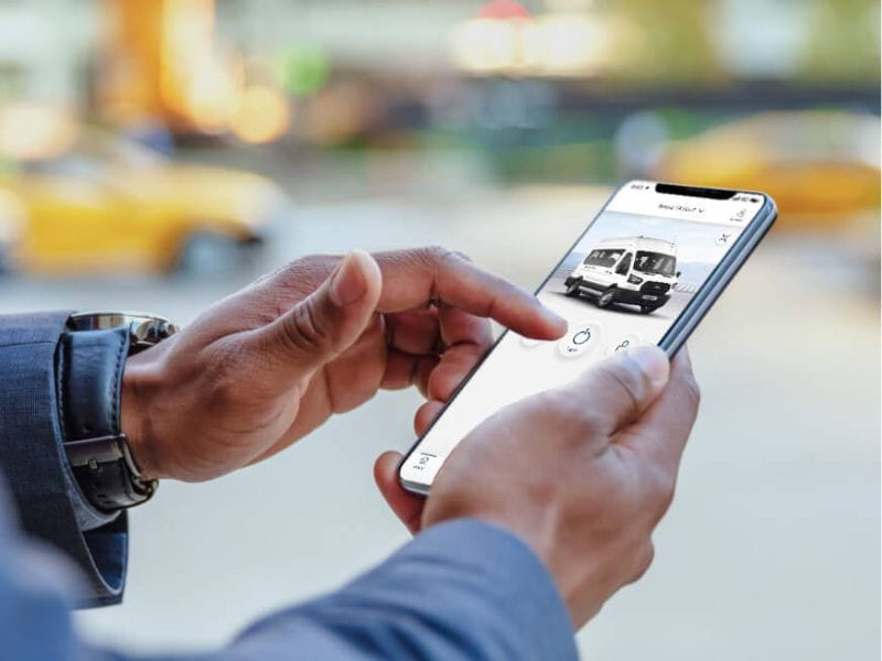 Mãos segurando celular exibindo mini van Ford Transit