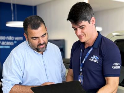 Funcionário Ford Forbel conversando com cliente diante de notebook