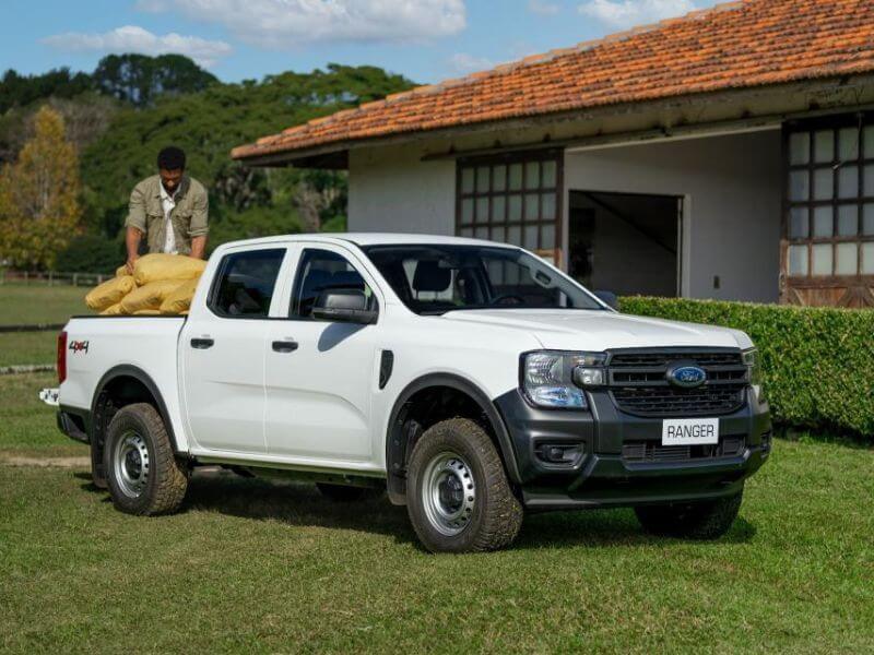 Picape Ford Ranger em ambiente campestre tendo sua carroceria carregada