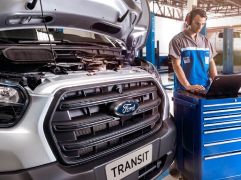 Mecânico avaliando parte interna do capô do veículo Ford Transit