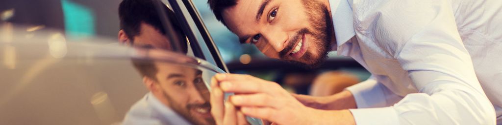 hombre sonriente alisando la carrocería brillante de un vehículo Ford