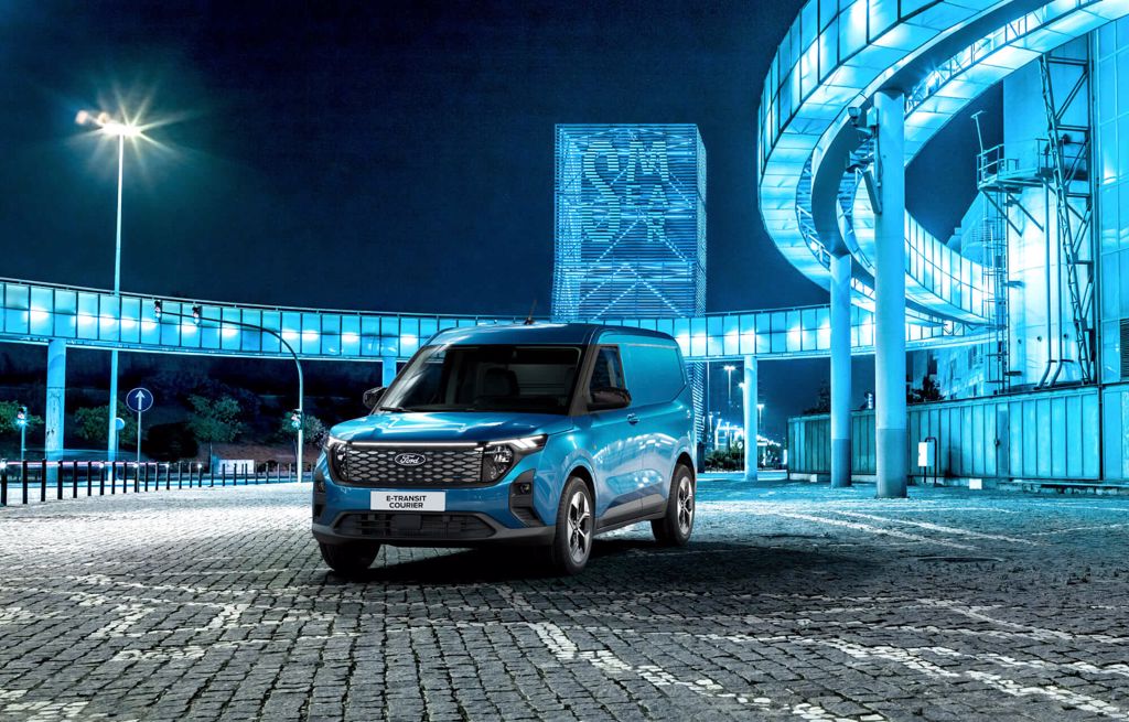 Ford E-Transit Courier bleu devant un bâtiment éclairé en bleu